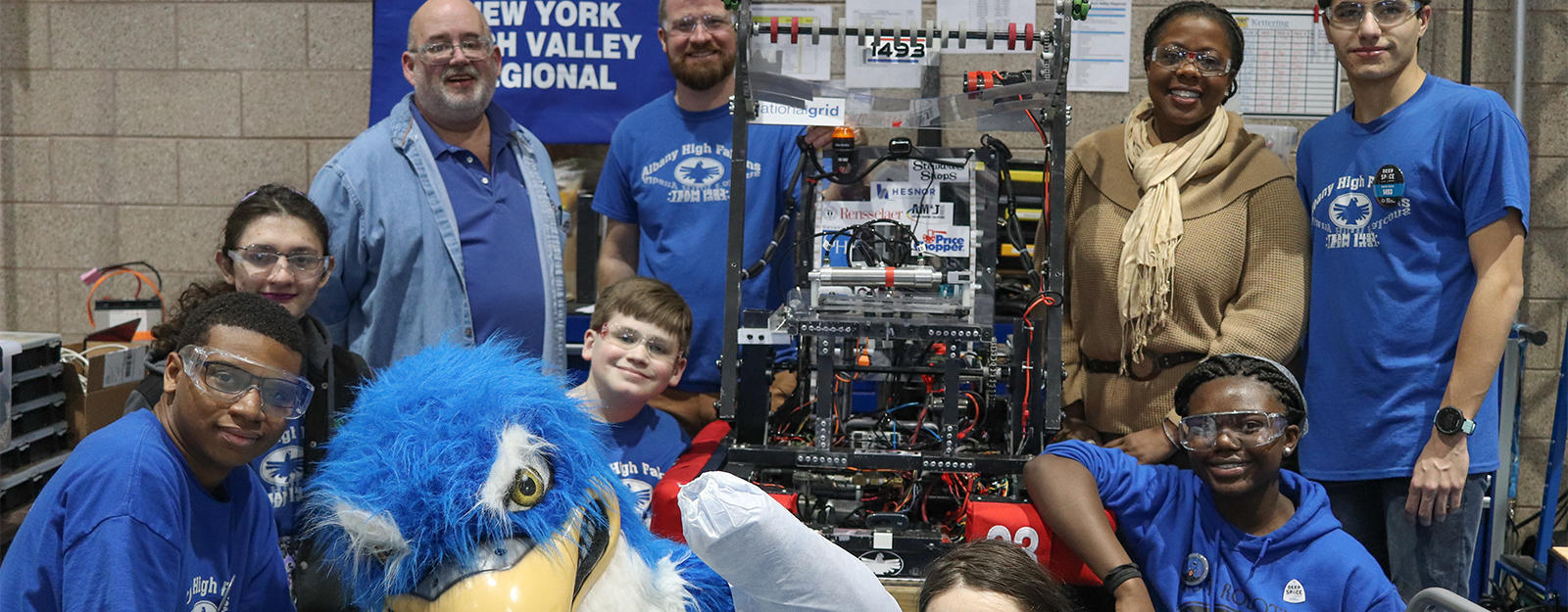 Robotics team posing for a group picture with the ʿ High Falcon mascot.